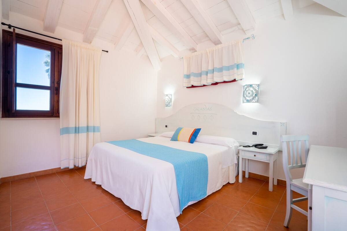 Un dormitorio con cama, escritorio y silla.