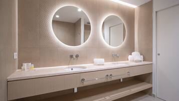 A modern bathroom with two sinks, a large mirror, and a towel rack.