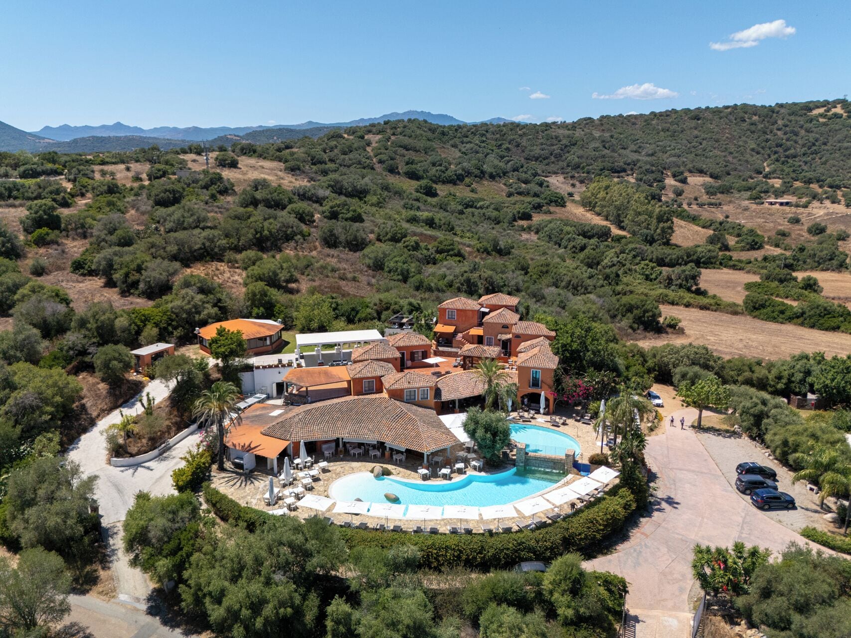 A resort with a swimming pool, multiple villas, and a mountainous backdrop.