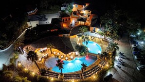 Vista aérea de un resort con varias piscinas, zonas de estar al aire libre y un estacionamiento.