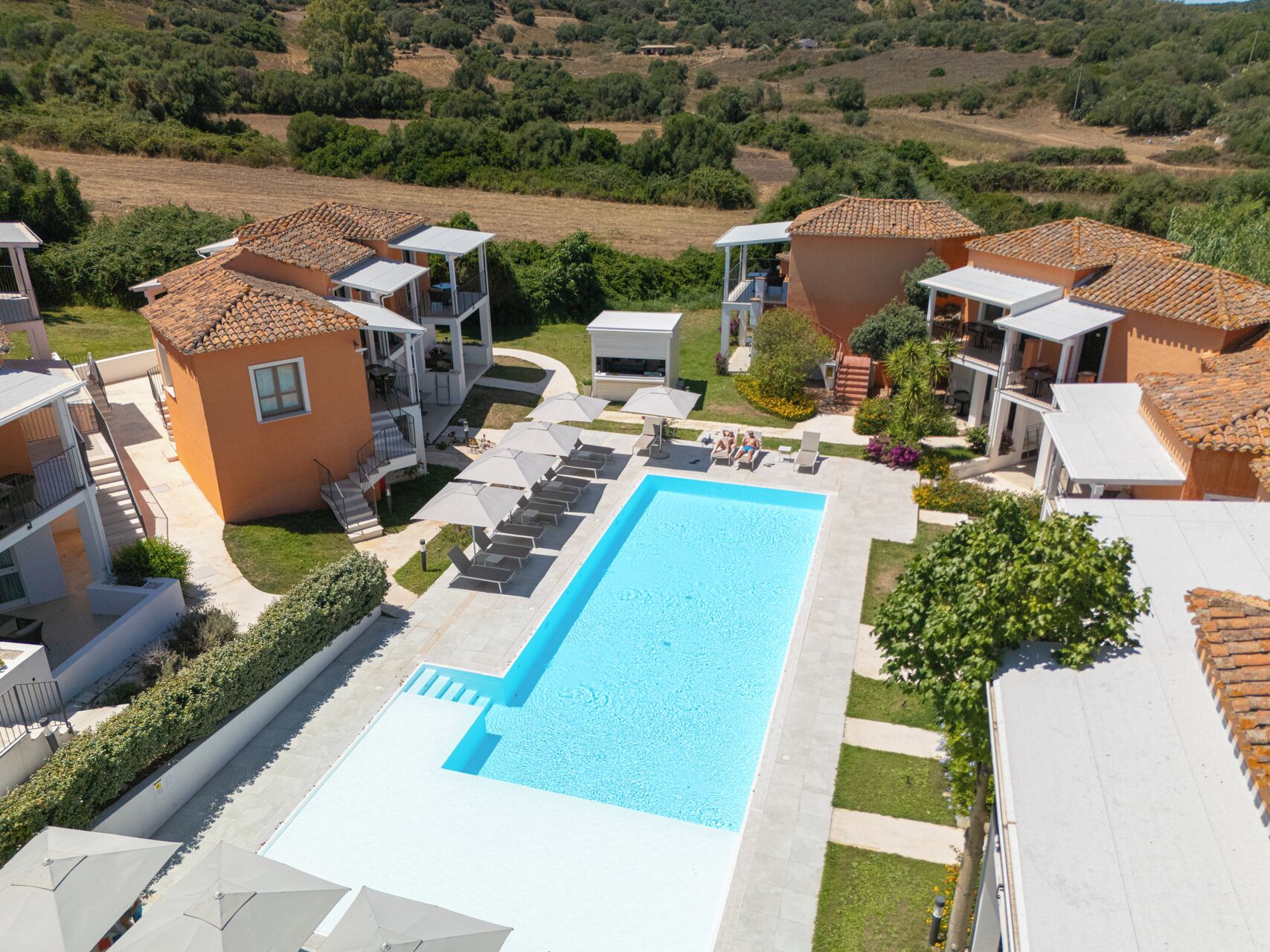 A resort with a swimming pool, multiple guest rooms, and a landscaped garden.