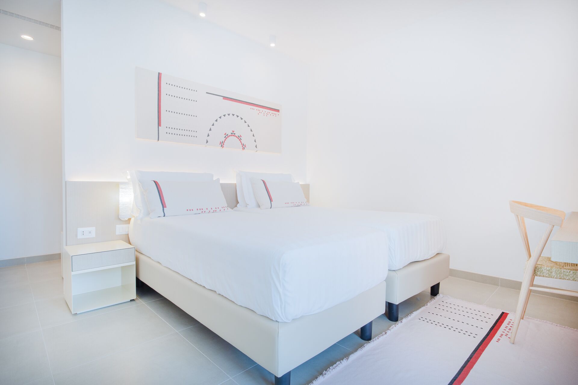 Un dormitorio moderno con una cama grande, mesitas de noche y una obra de arte colgada en la pared.