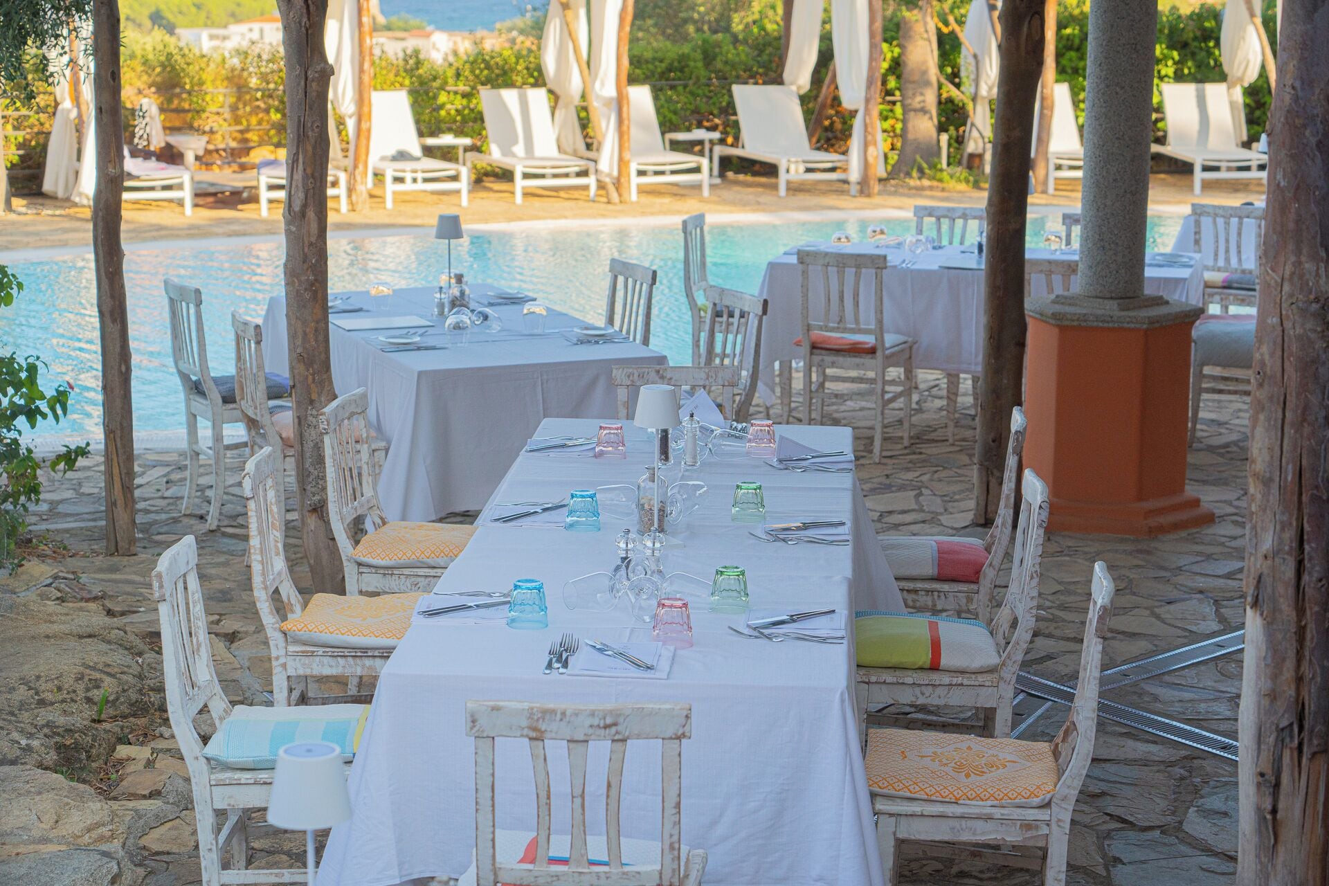 An outdoor dining area with tables set for a meal, overlooking a pool.