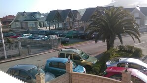 A parking area with several cars, a palm tree, and houses in the background. - Hotel Costa Cántabra (Argonos)