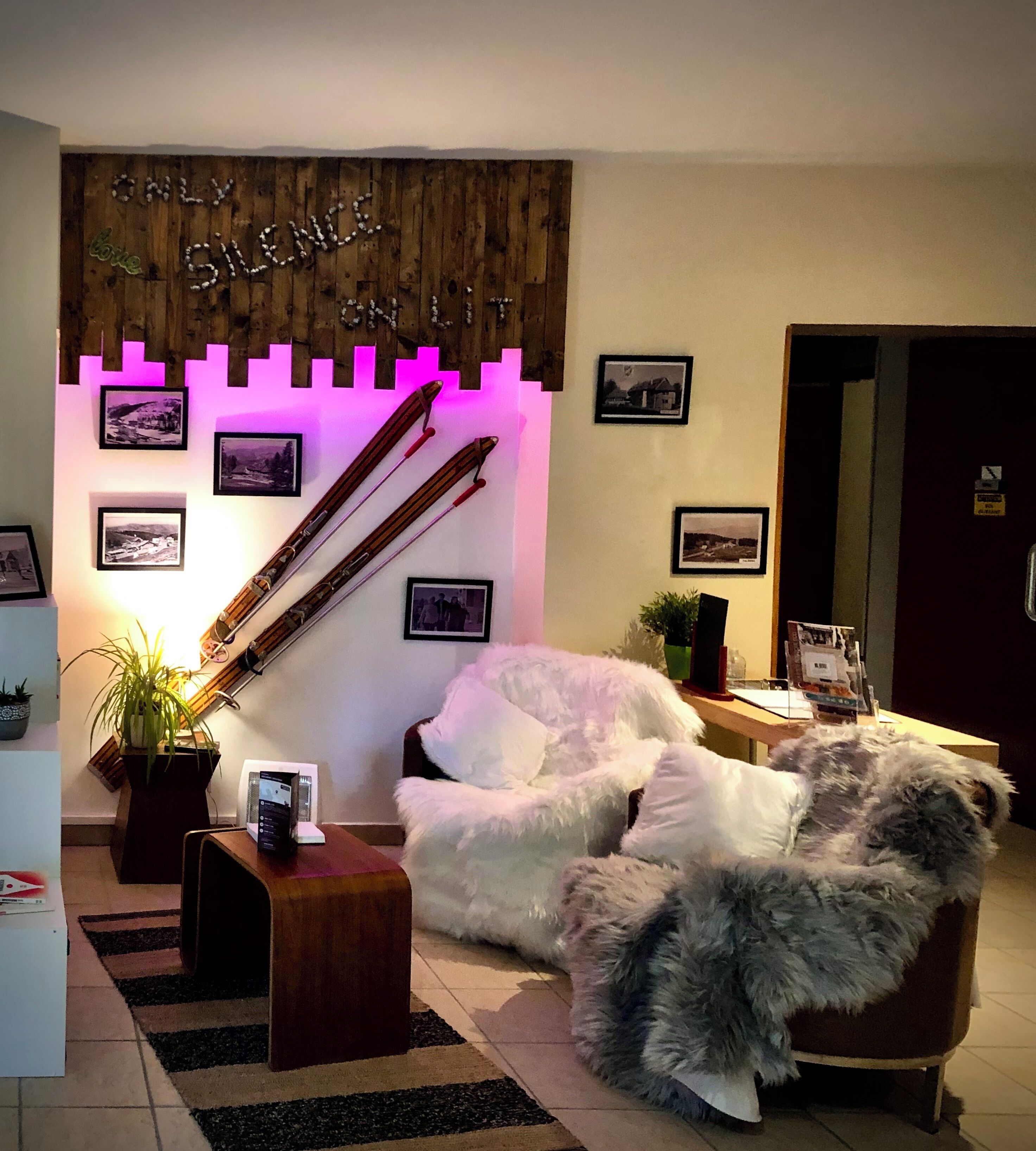 Een gezellige woonkamer met een houten accentmuur, een witte fauteuil en een zacht tapijt.
