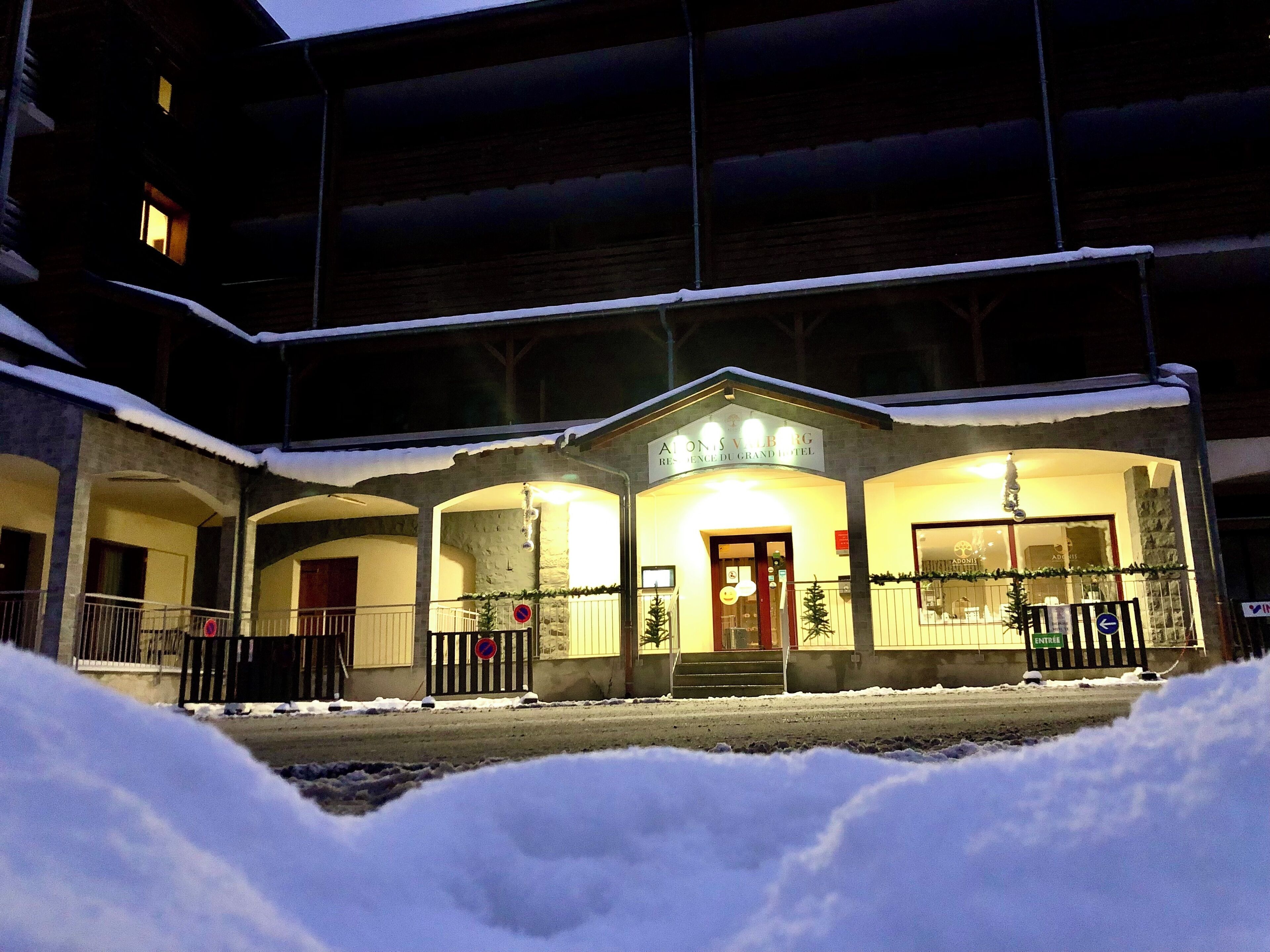 Un hotel con entrada cubierta, zona de estar al aire libre y nieve en el suelo.