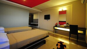 A modern hotel room with two beds, a desk, a chair, a TV, and a mirror. - The Viceroy Comforts (Mysore)