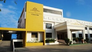 A hotel with a yellow and white facade, a grand entrance, and a clear sky. - The Viceroy Comforts (Mysore)