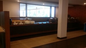 A modern kitchen area with a countertop, various kitchen appliances, and a window providing natural light. - The Viceroy Comforts (Mysore)