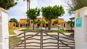 A gated entrance to a building with a pool and outdoor seating area.