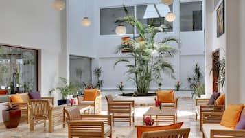 A spacious lobby with wooden furniture, potted plants, and hanging lights.