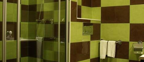 A bathroom with a glass-enclosed shower, a white toilet, and a sink with a mirror above it.