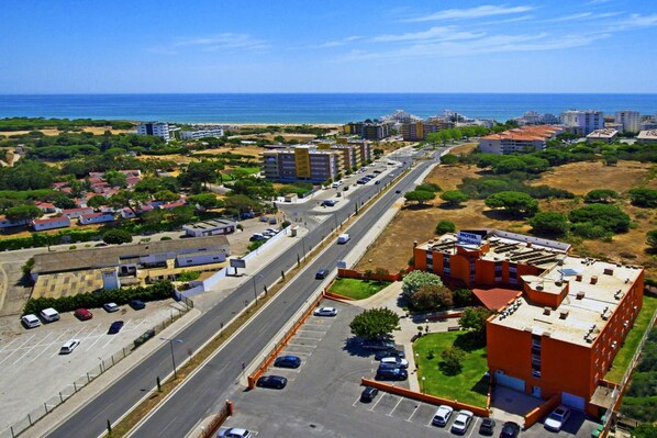 An aerial view of a coastal area with a hotel, roads, and surrounding buildings.
