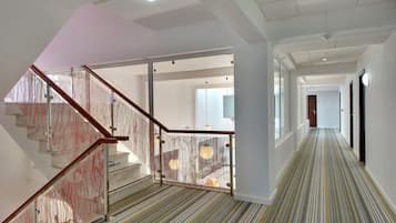 Un interno moderno con una scala, porte in vetro e una moquette a righe.
