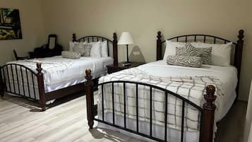 Two wooden beds with metal frames, white bedding, and decorative pillows.