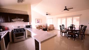 Una cocina amplia con una isla central, armarios de madera oscura y electrodomésticos de acero inoxidable.