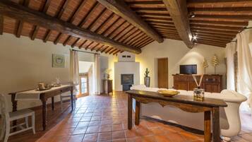 A spacious living area with a rustic wooden ceiling, a central table, and a sofa.