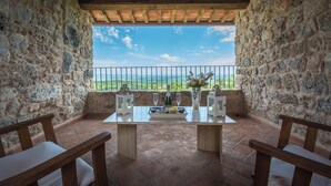 Una terraza de paredes de piedra con una mesa para dos, una botella y velas.