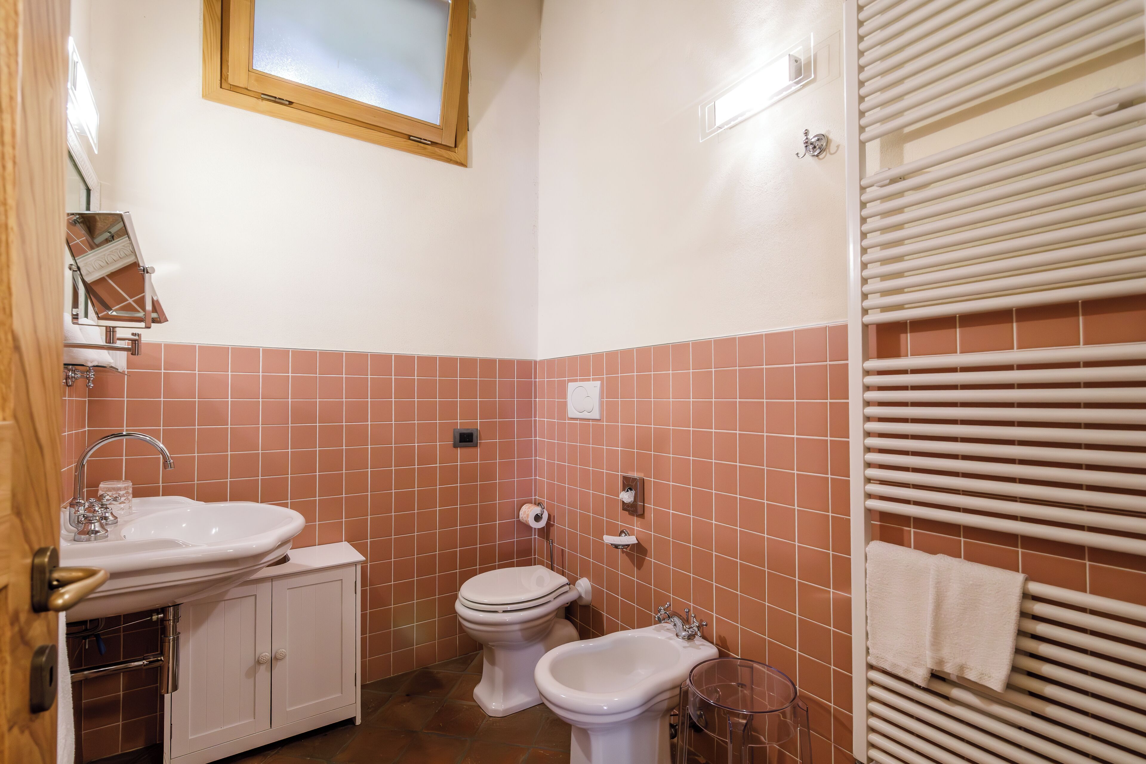 Casa de banho com lavatório, sanita, bidé e suporte para toalhas.