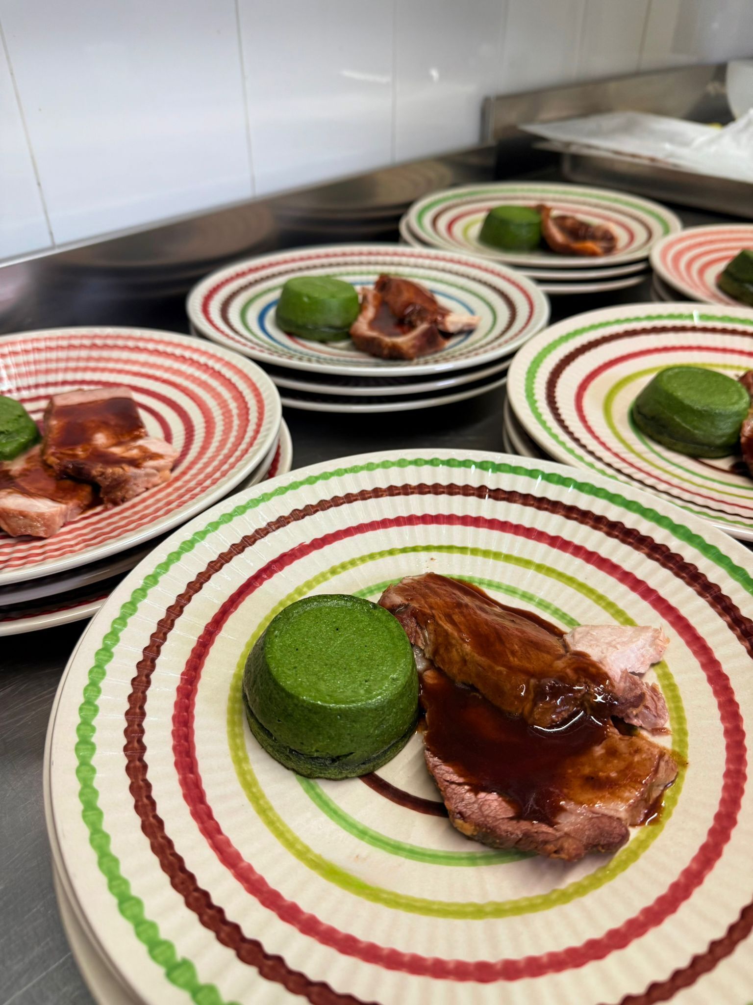 A kitchen with multiple plates of food, including meat and a green item, arranged on a counter.