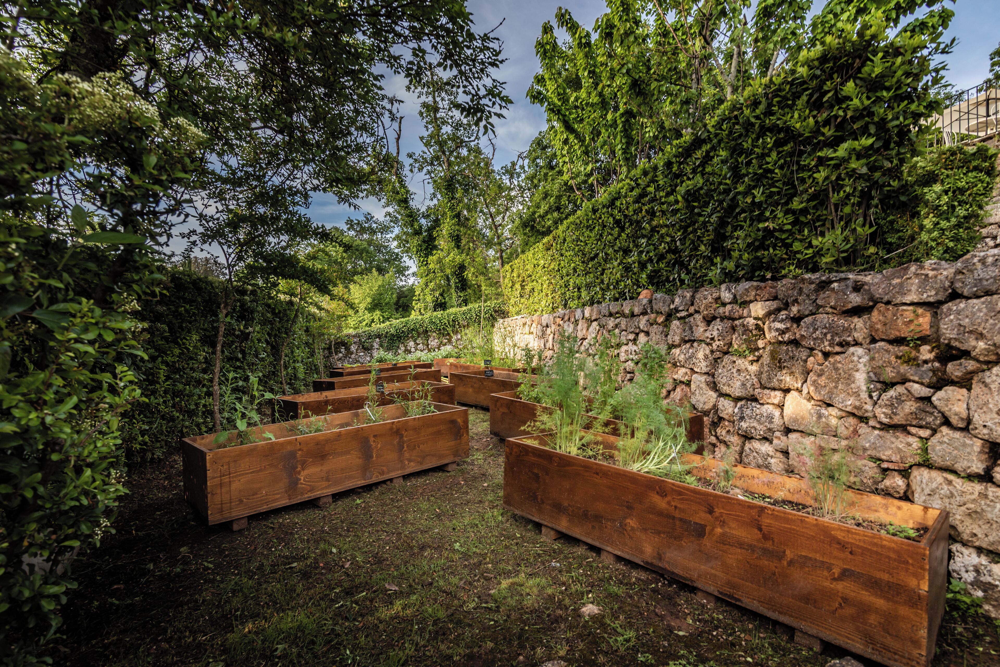 Un jardin agrémenté de jardinières en bois surélevées et d’un mur en pierre.