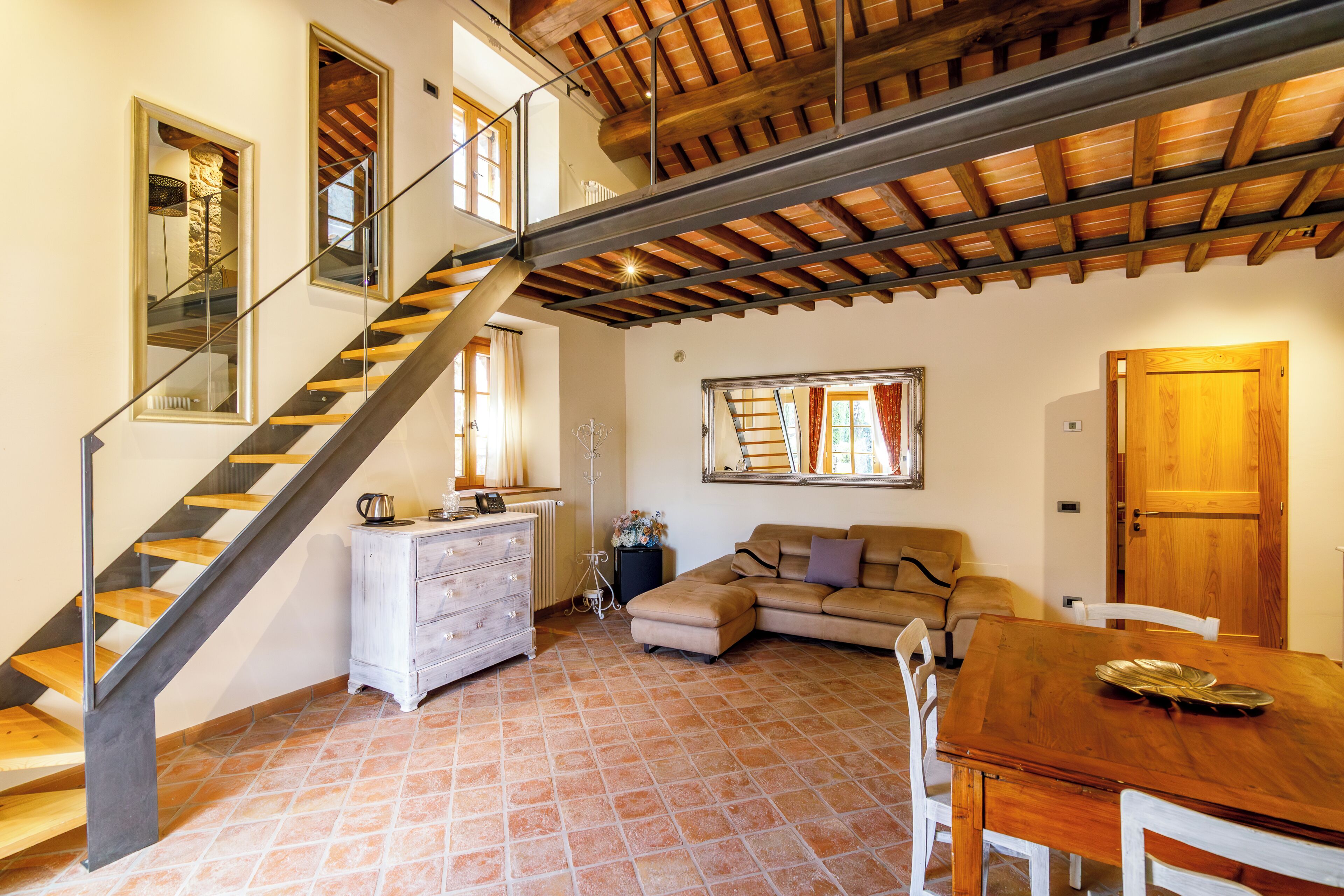 A spacious living area with a wooden staircase, a dining table, and a sofa.