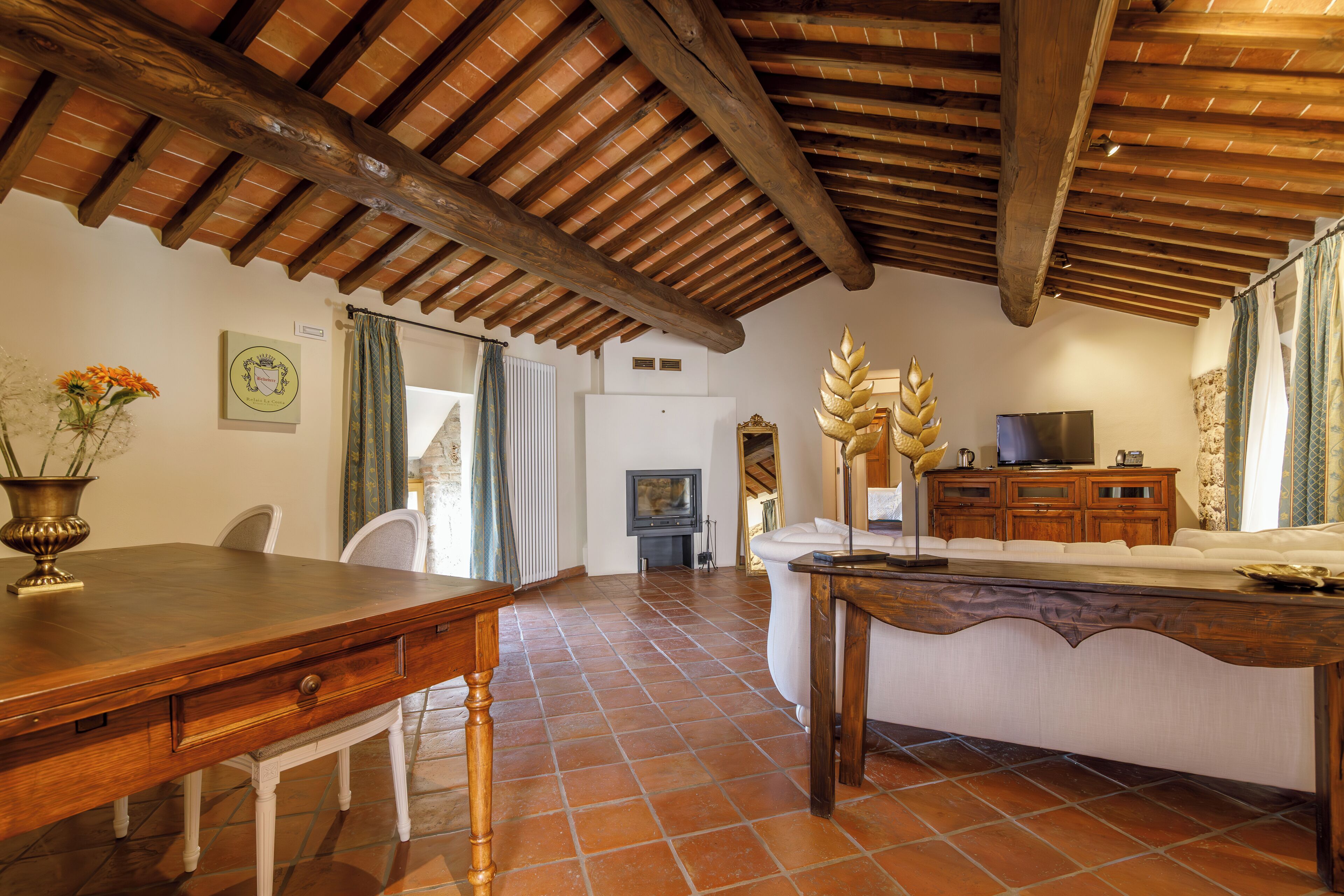 A spacious living area with a wooden ceiling, a dining table, and a sofa.