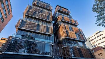 Um edifício com vários andares e design arquitetônico moderno, com grandes janelas de vidro e grades de metal.