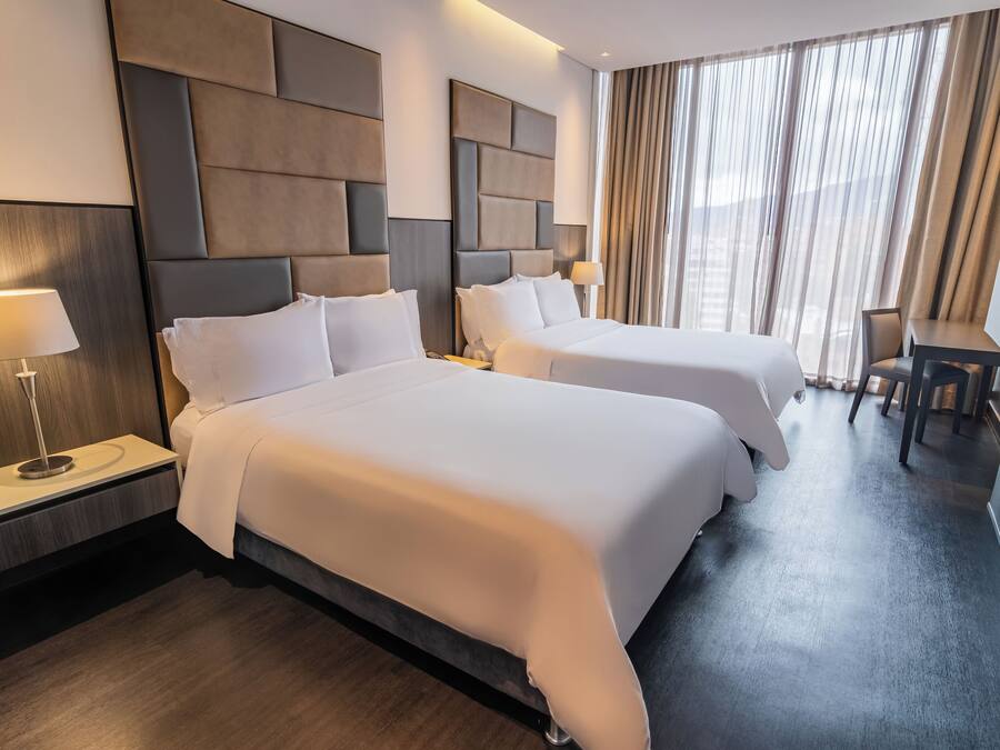 Habitación de hotel con dos camas, un escritorio y una silla.