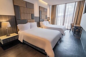 Een hotelkamer met twee bedden, een bureau en een stoel.
