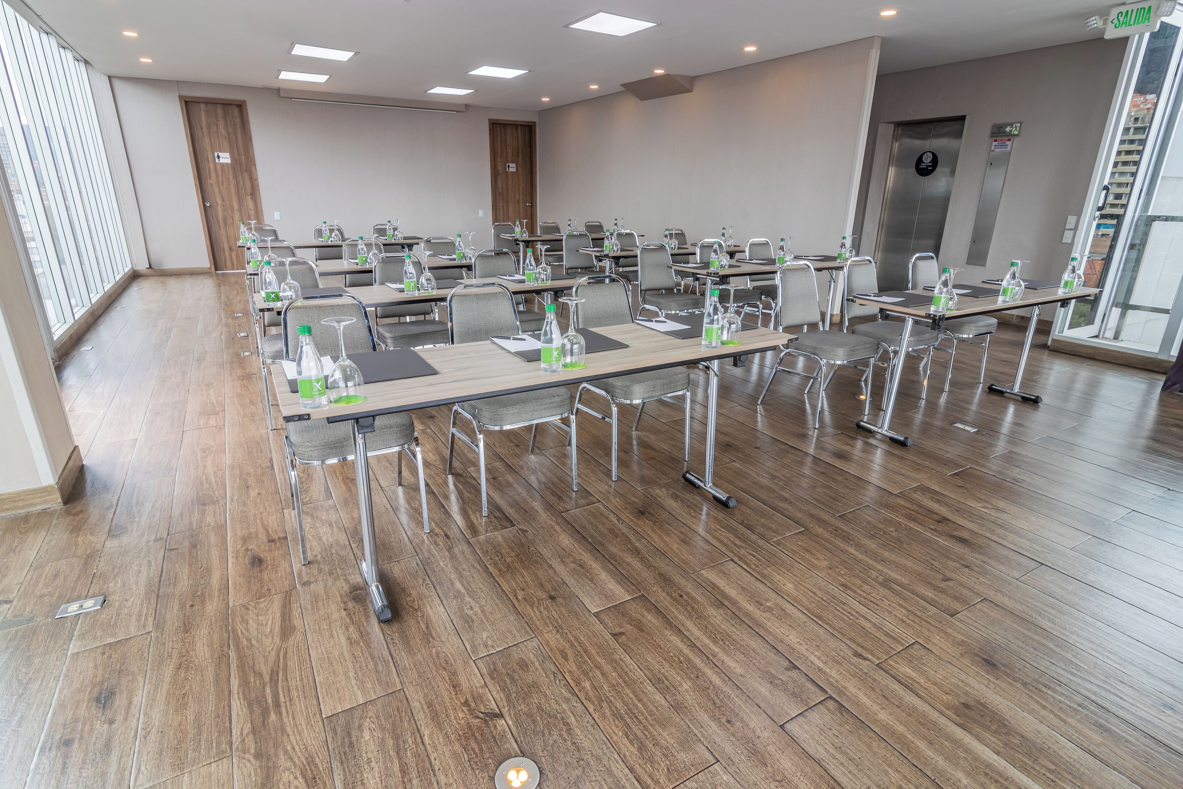 Un salón de conferencias con varias mesas, sillas y botellas de agua.