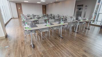 A conference room with multiple tables, chairs, and water bottles.