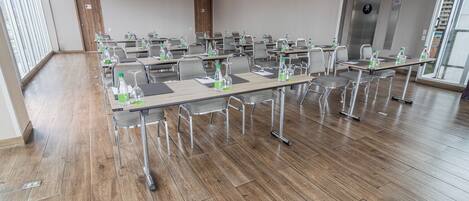 A conference room with multiple tables, chairs, and water bottles.