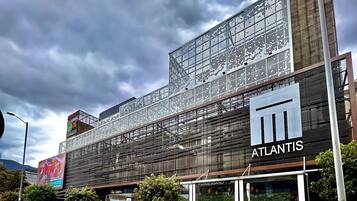 Un edificio moderno con un llamativo letrero de "Atlantis", que presenta una fachada tipo entramado y un gran anuncio publicitario en la parte superior.
