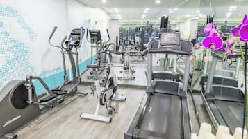 Ett gym med olika träningsmaskiner, en vägg med speglar och ett trägolv.