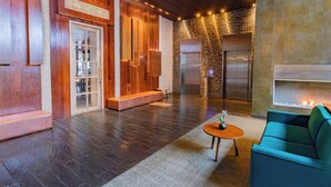 Un hall d’entrée moderne avec un comptoir d’accueil en bois, un espace salon et une cheminée.
