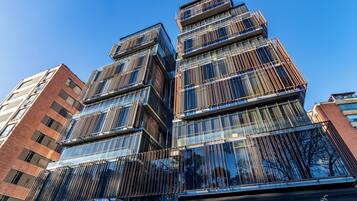Un immeuble à étages doté d’une architecture moderne, caractérisé par de grandes fenêtres en verre et une façade structurée.
