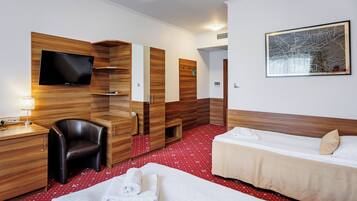 A hotel room with a TV, a desk, a chair, two beds, and a map on the wall.