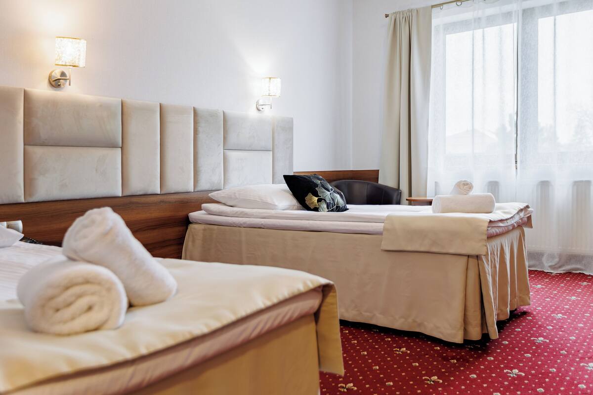 Habitación de hotel con dos camas, un cabecero grande y una alfombra roja.