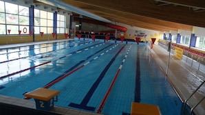 Una piscina interior con carriles de natación, un puesto de socorrista y un tobogán.