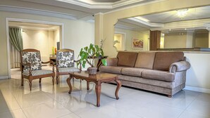 A living room with a sofa, two armchairs, a coffee table, and a potted plant. - Pousada Serra Valle (Gramado)