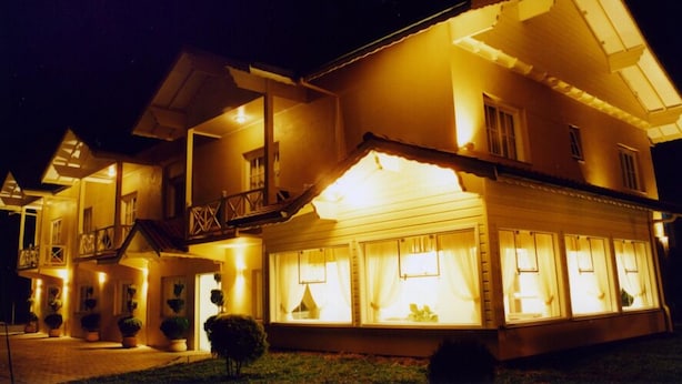 A two-story building with a balcony on the upper floor, large windows on the ground floor, and a well-lit entrance. - Pousada Serra Valle (Gramado)
