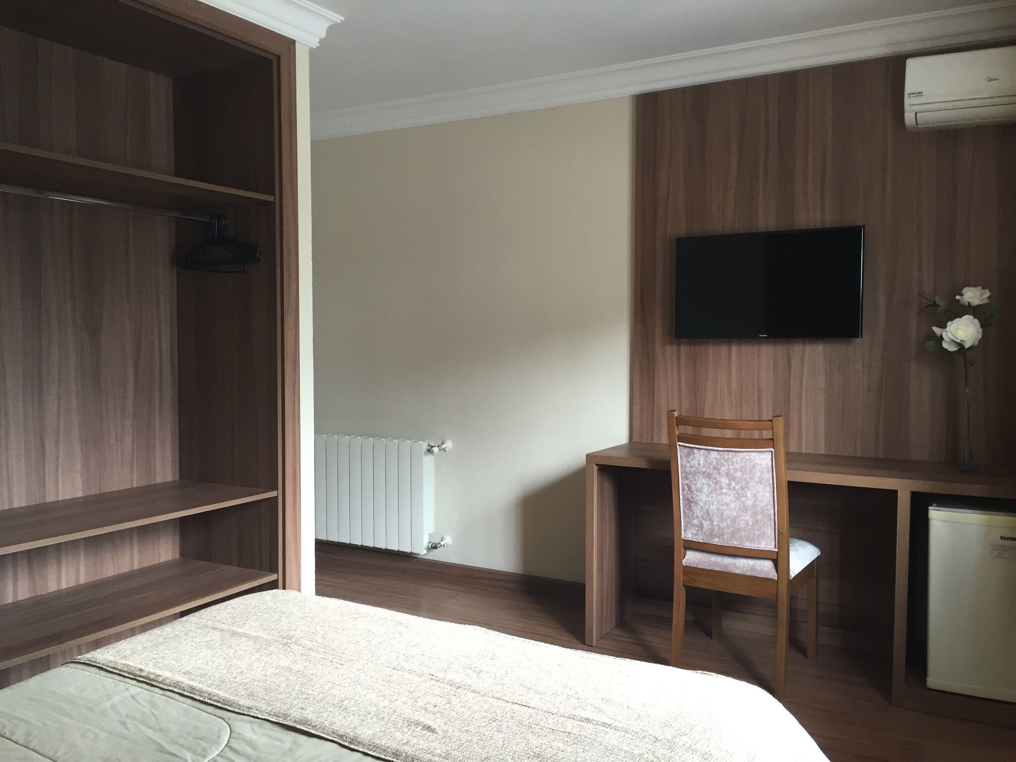 Habitación de hotel con cama, escritorio, silla, televisor y armario.