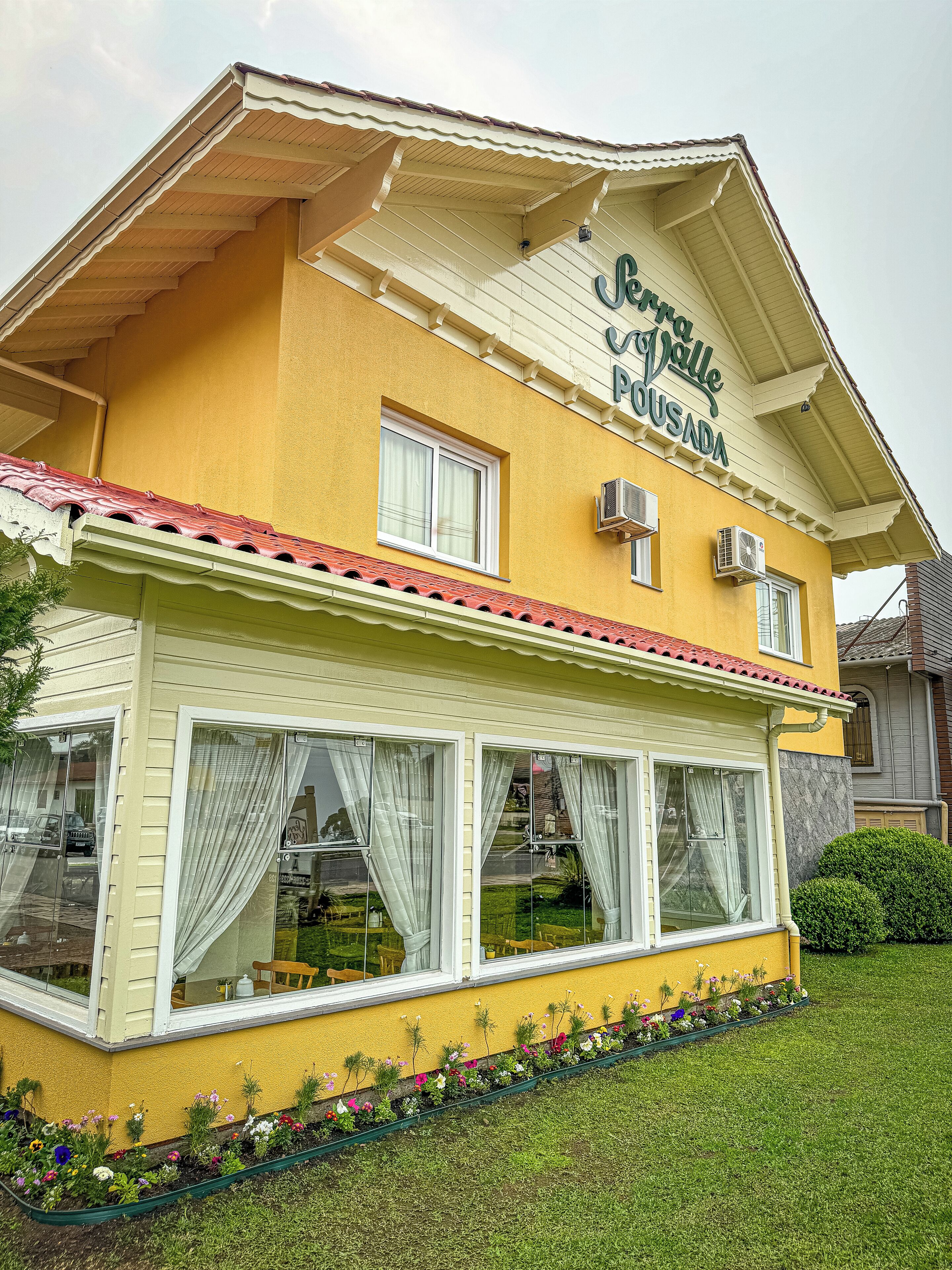 Un bâtiment jaune sur lequel on peut lire l’inscription : « Pension Villa Pousada ».