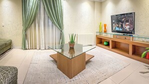 A modern living room with a glass-top coffee table, a sofa, a TV on the wall, and a decorative plant. - Pousada Serra Valle (Gramado)
