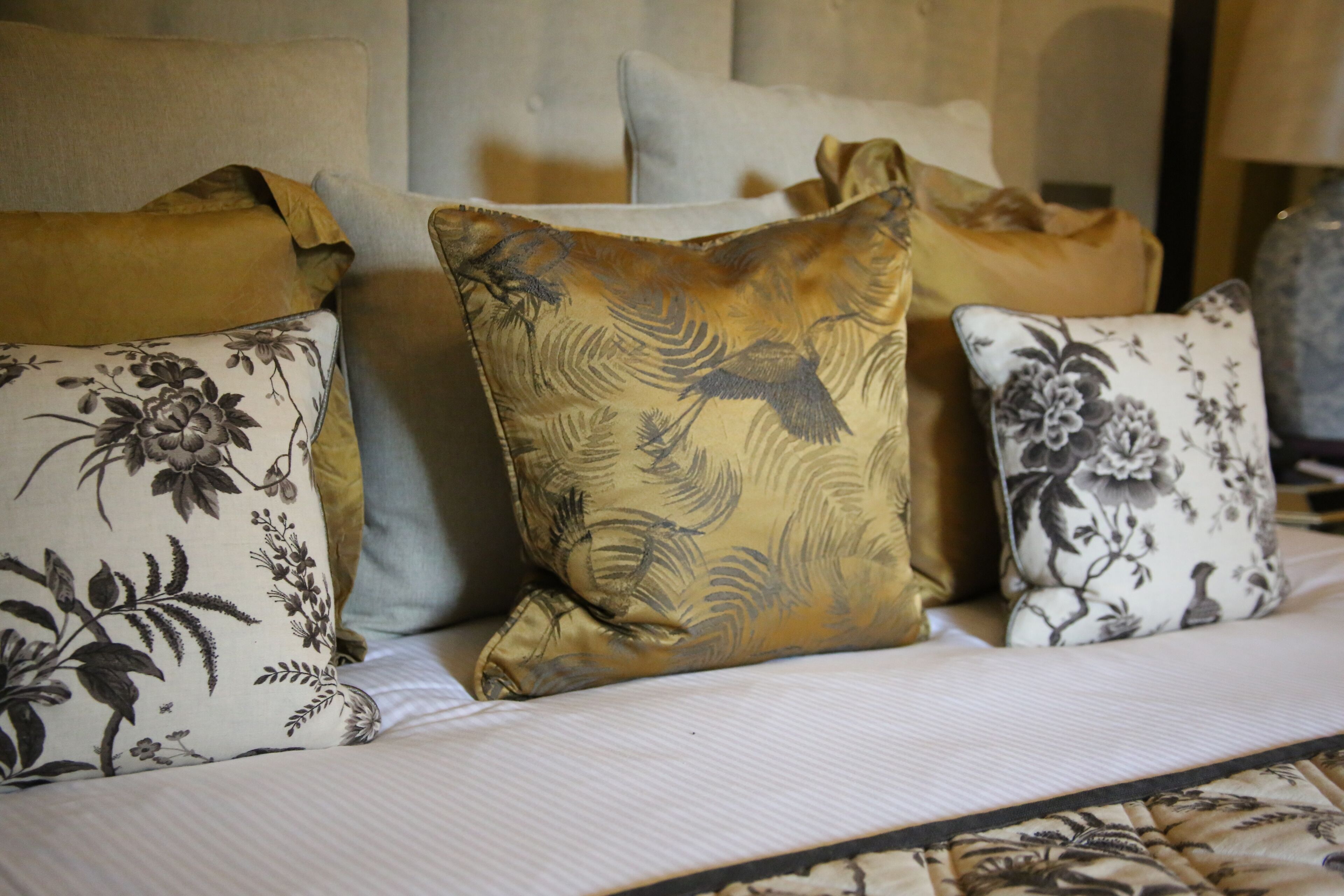 A bed with multiple pillows featuring floral and bird designs.