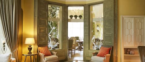 A room with a round glass coffee table, two armchairs, a sofa, and a lamp.