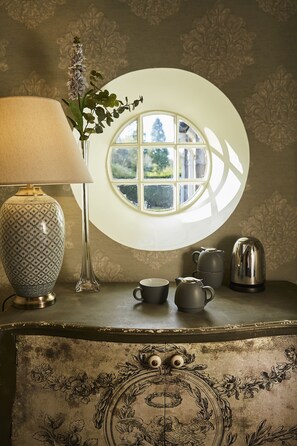 A vintage-style table with a lamp, a vase with flowers, a teapot, and a cup. - Cairn Lodge (Auchterarder)