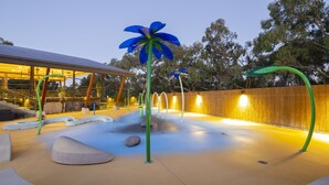 A modern outdoor area with a pool, seating, and a wooden fence. - Alivio Tourist Park Canberra (O'Connor)