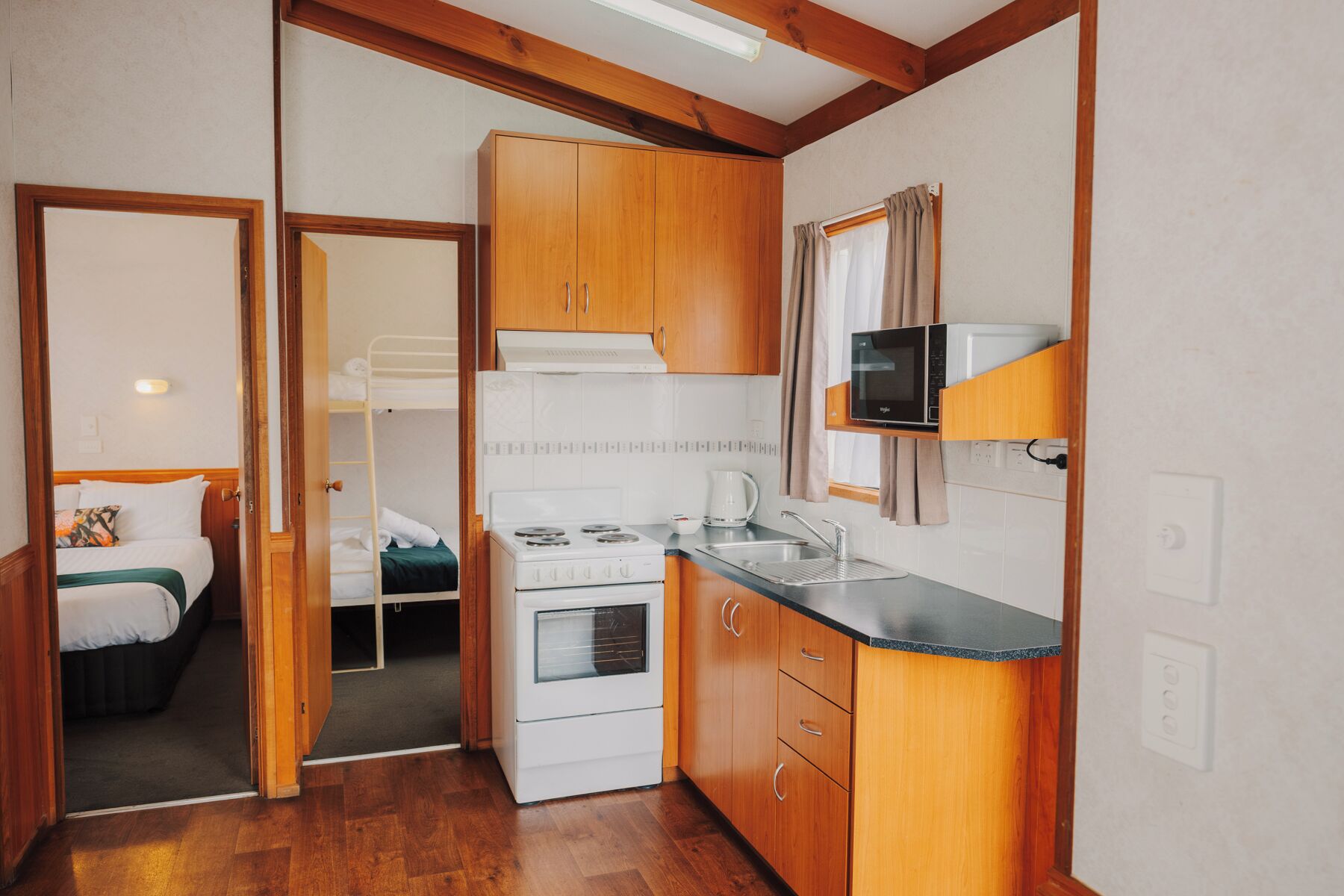 A compact kitchen with wooden cabinets, a stove, and a microwave.